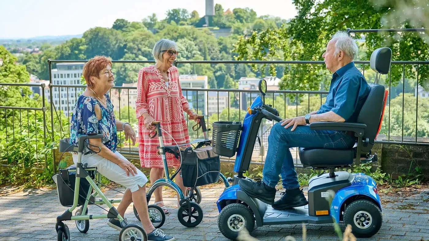 An der Sparrenburg: ein Mann auf dem Elektromobil im Gespräch mit zwei Frauen mit Rollator