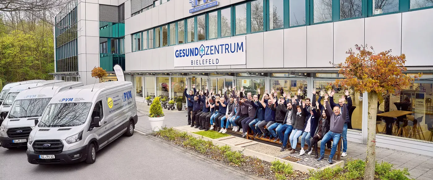 Das PVM-Team vor dem GesundZentrum am Südring in Bielefeld, daneben die Lieferfahrzeuge