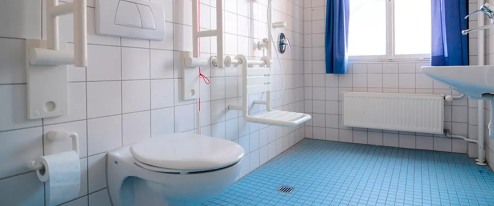 Barrierefreies Badezimmer mit Toilette, Duschsitz und unterfahrbarem Waschbecken
