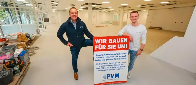 Markus Wendler und Bernd Reger mit dem Schild „Wir bauen für Sie um!“