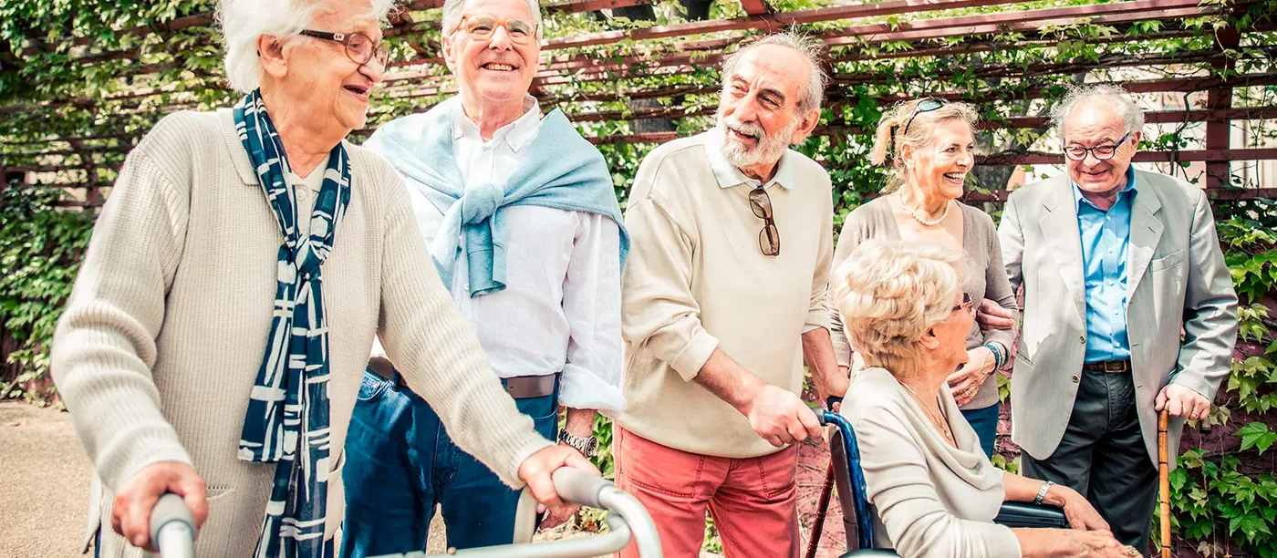 Vier ältere Menschen gehen lachend gemeinsam spazieren