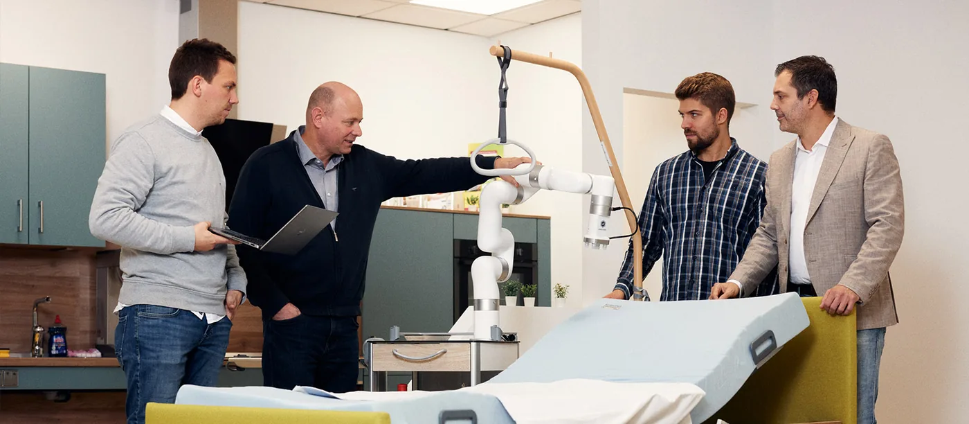 Markus Wendler und Forscher der FH Bielefeld am Pflegebett mit Roboterarm