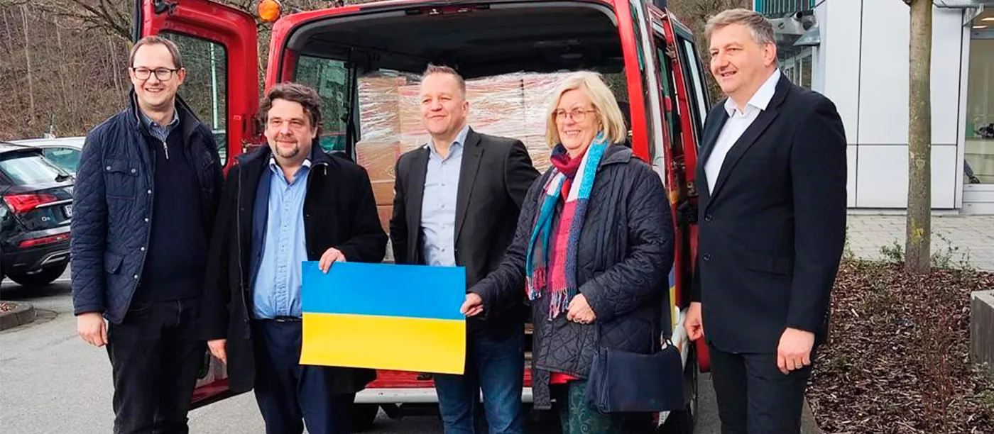 Helferinnen und Helfer mit ukrainischer Flagge vor dem Transportfahrzeug