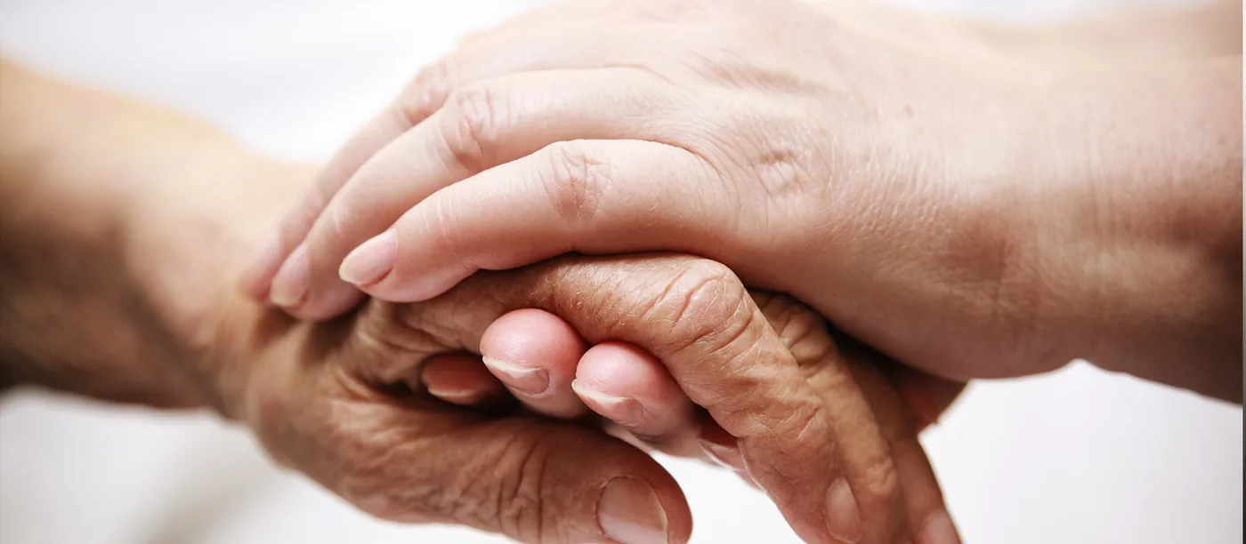 Zwei Hände halten die Hand eines älteren Menschen