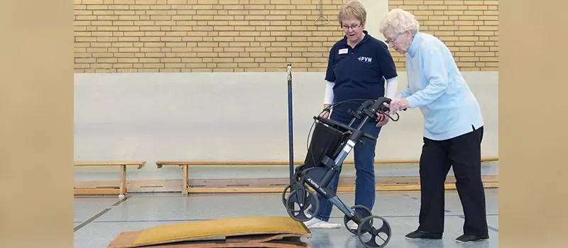 Rollatortraining: Eine Trainerin übt mit einer Seniorin das Überwinden einer Schwelle