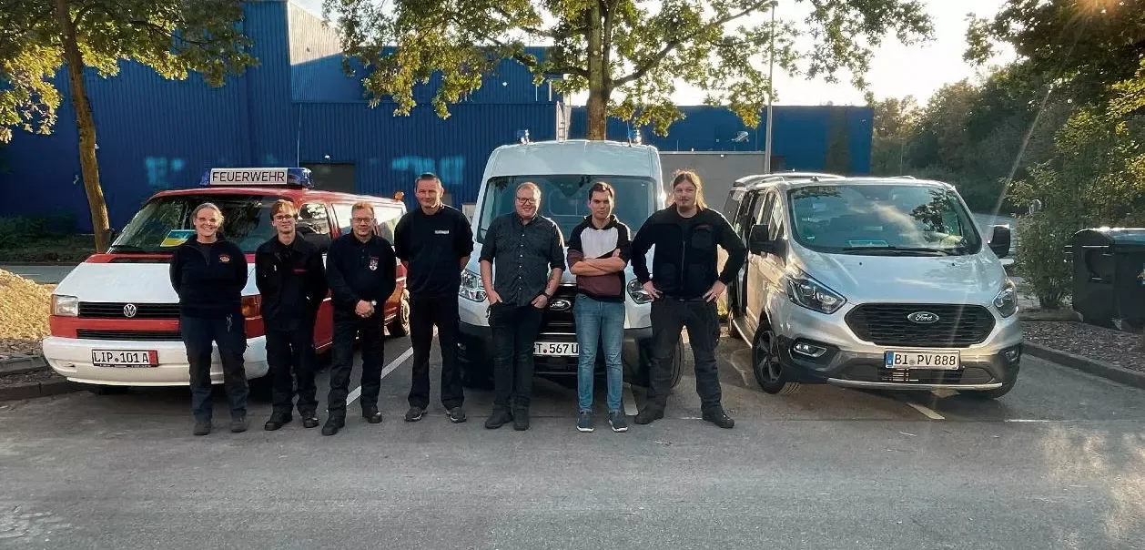 Helfer des Netzwerks OWL vor dem gespendeten Krankentransportwagen